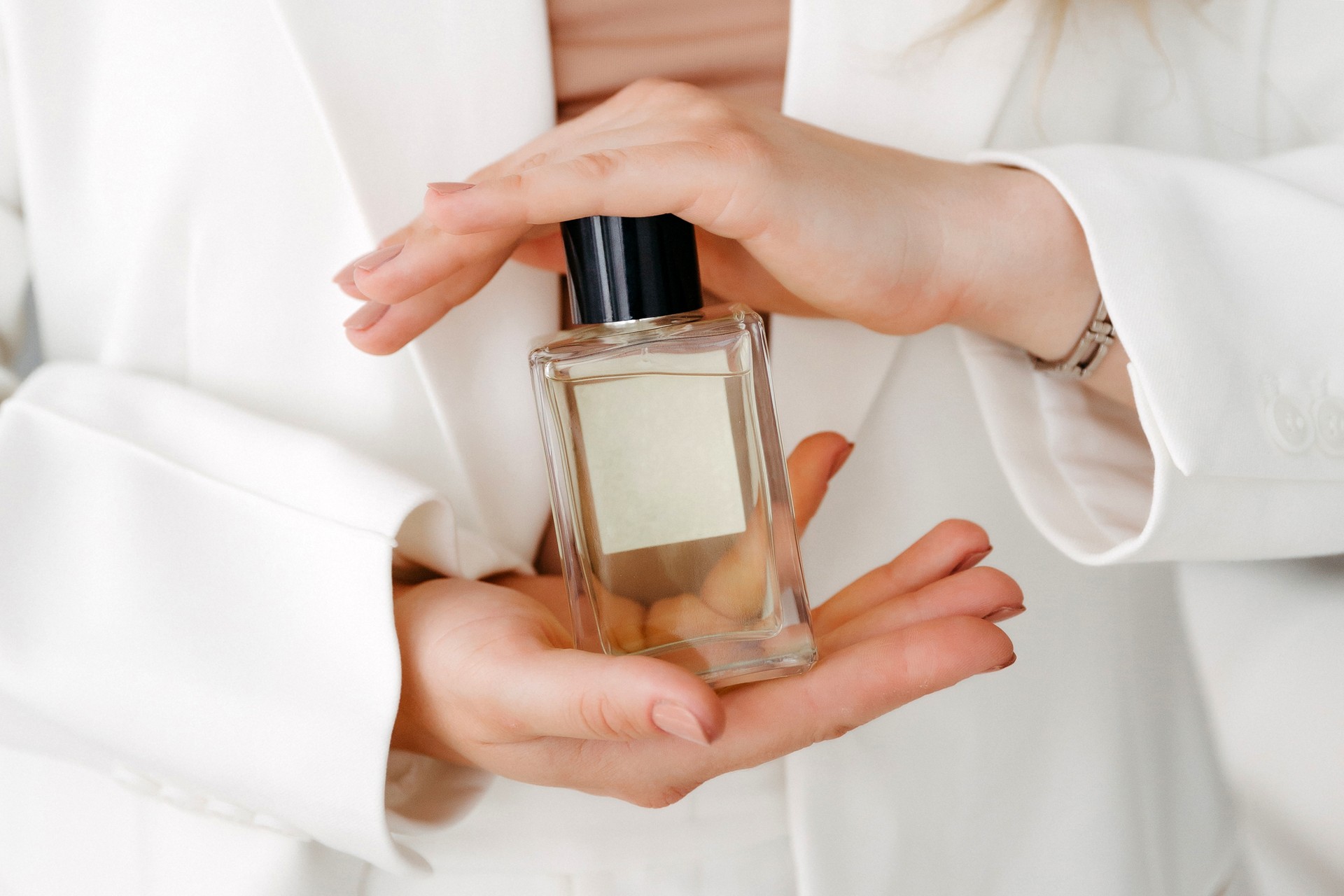 Hands of a beautiful young woman with a bottle of floral perfume